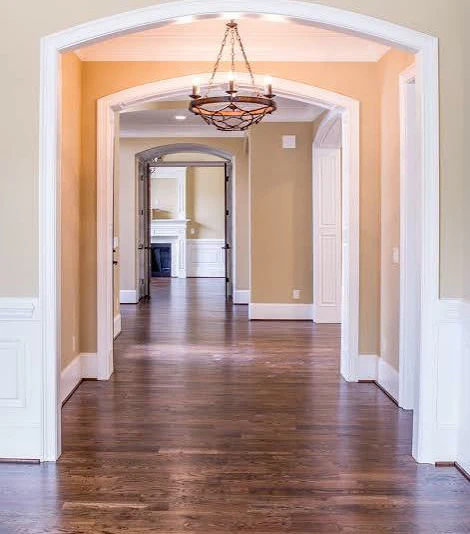 Dark-stained hardwood running under a row of archways in a hallway