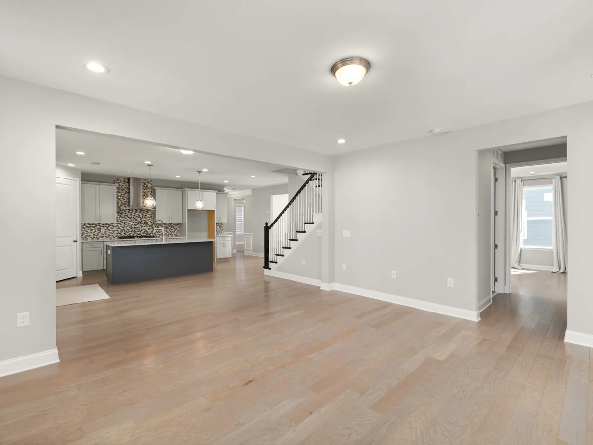 Open-concept main floor with light oak-look plank flooring running from the living area to the kitchen island