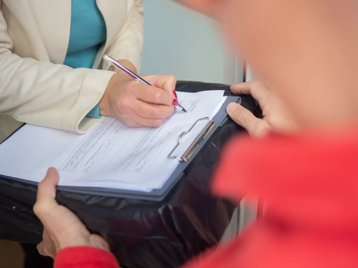 Person filling in a printed form on a clipboard with a pen