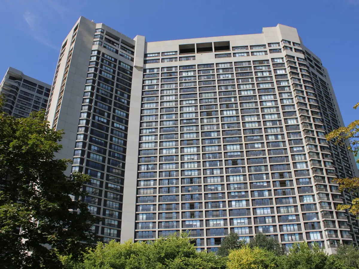 Low-angle view of a tall residential condo tower with rows of windows and balconies