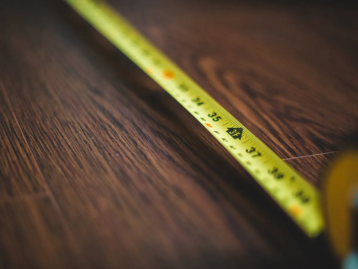 Yellow tape measure extended across a dark wood plank floor