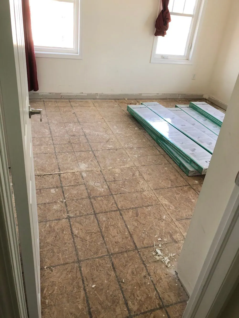 Room with bare subfloor and flooring boxes before installation