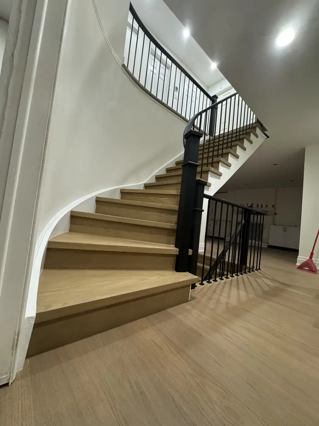 Curved staircase with oak treads and a black iron rail