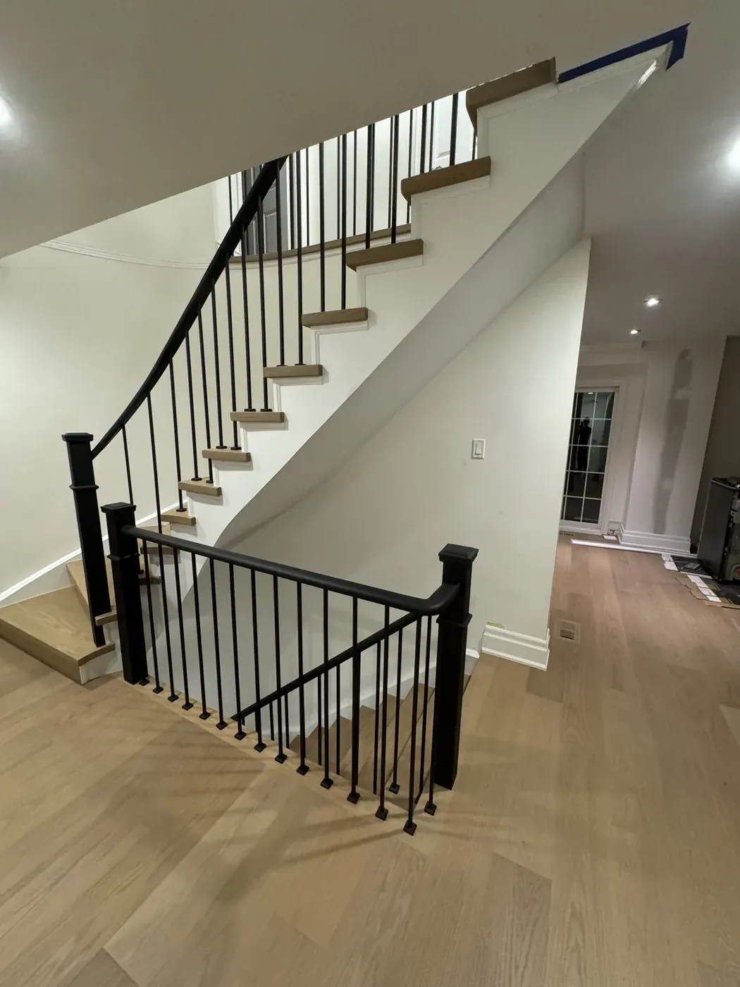 Oak floor and stairs with white risers and a black iron rail