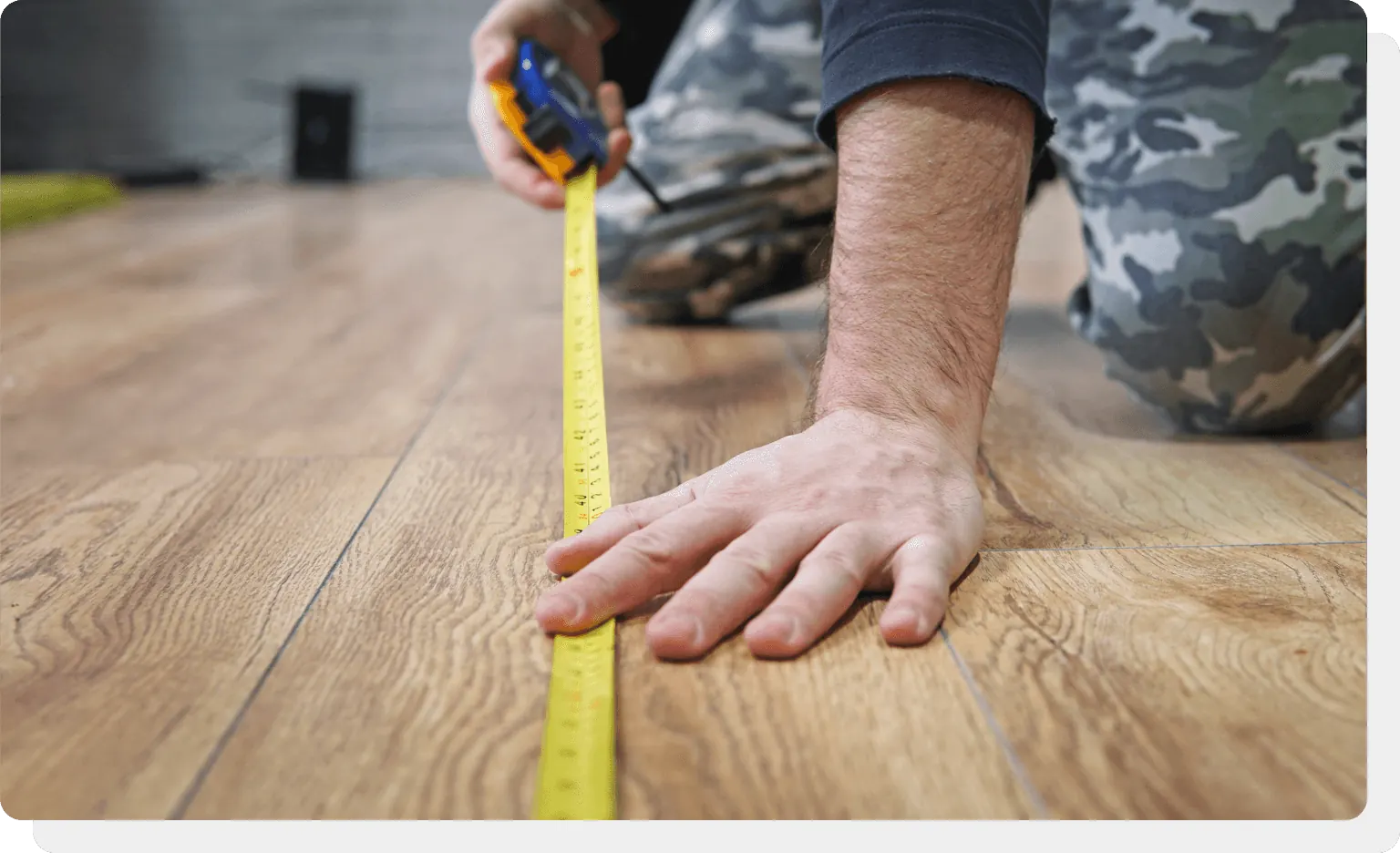 Installer running a tape measure across an oak floor