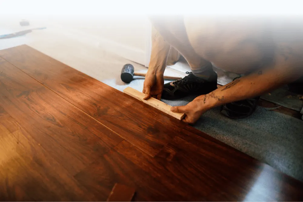 Installer tapping a hardwood board into position