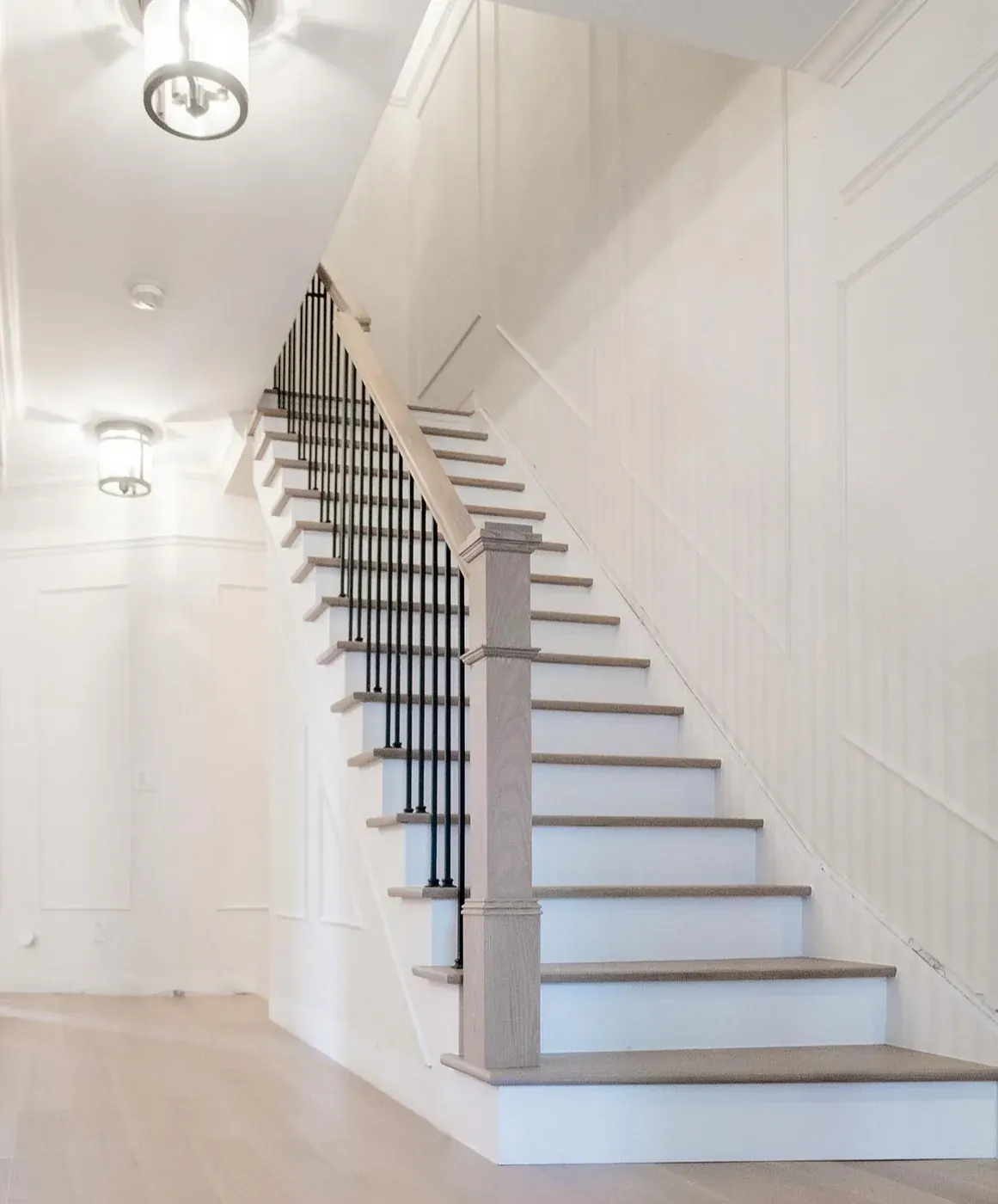 Staircase with pale oak treads, white risers and black iron pickets