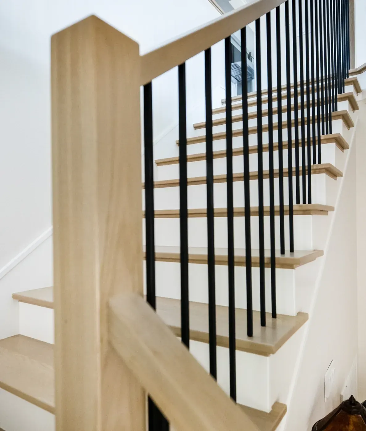 Staircase with light oak treads, white risers and black iron spindles
