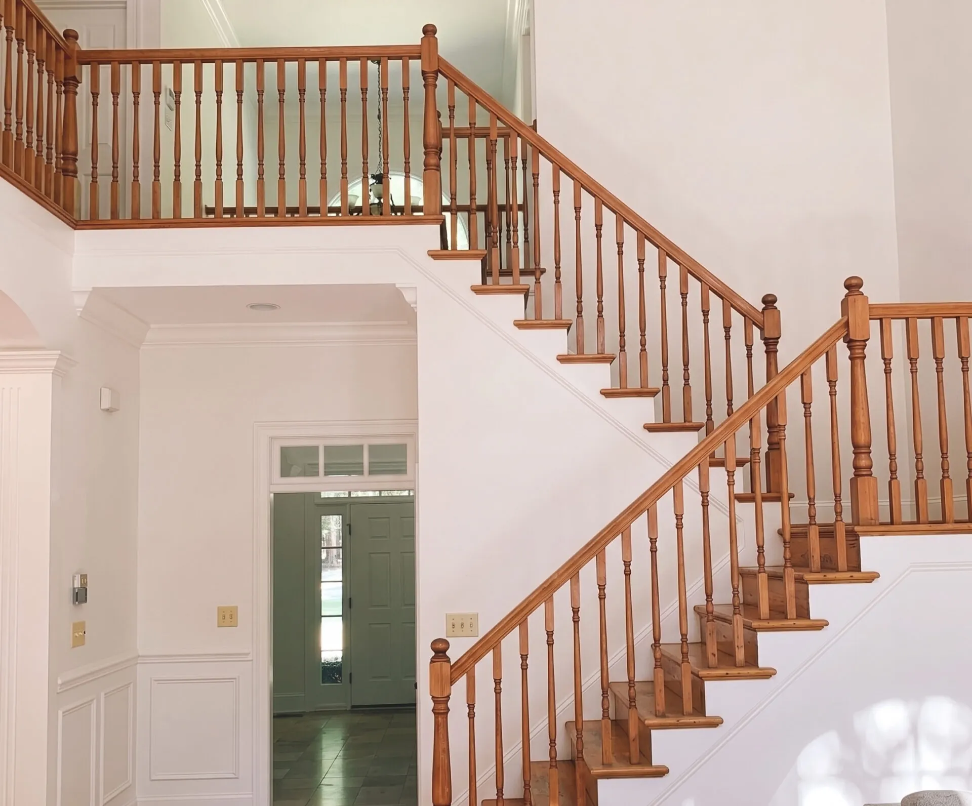 The same staircase before, with orange-stained wood spindles and rail